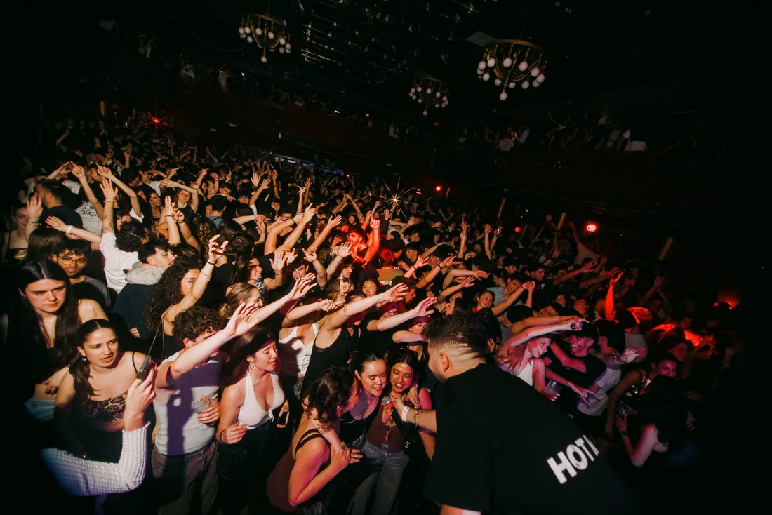 Sala llena con el público con las manos en alto